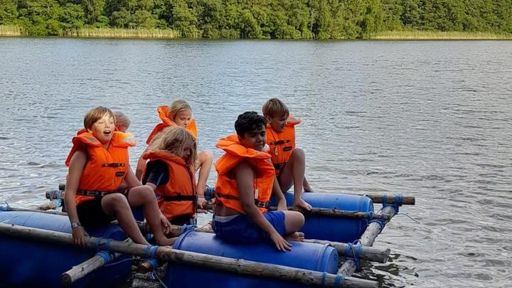 Juniorspejdere i redningsveste på selvbygget tømmerflåde